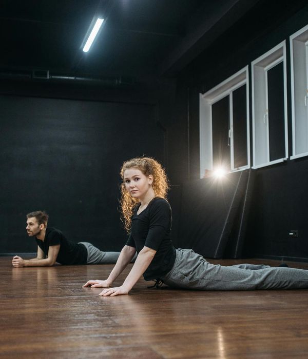 Woman practicing a balance pose in a warm amber studio setting.